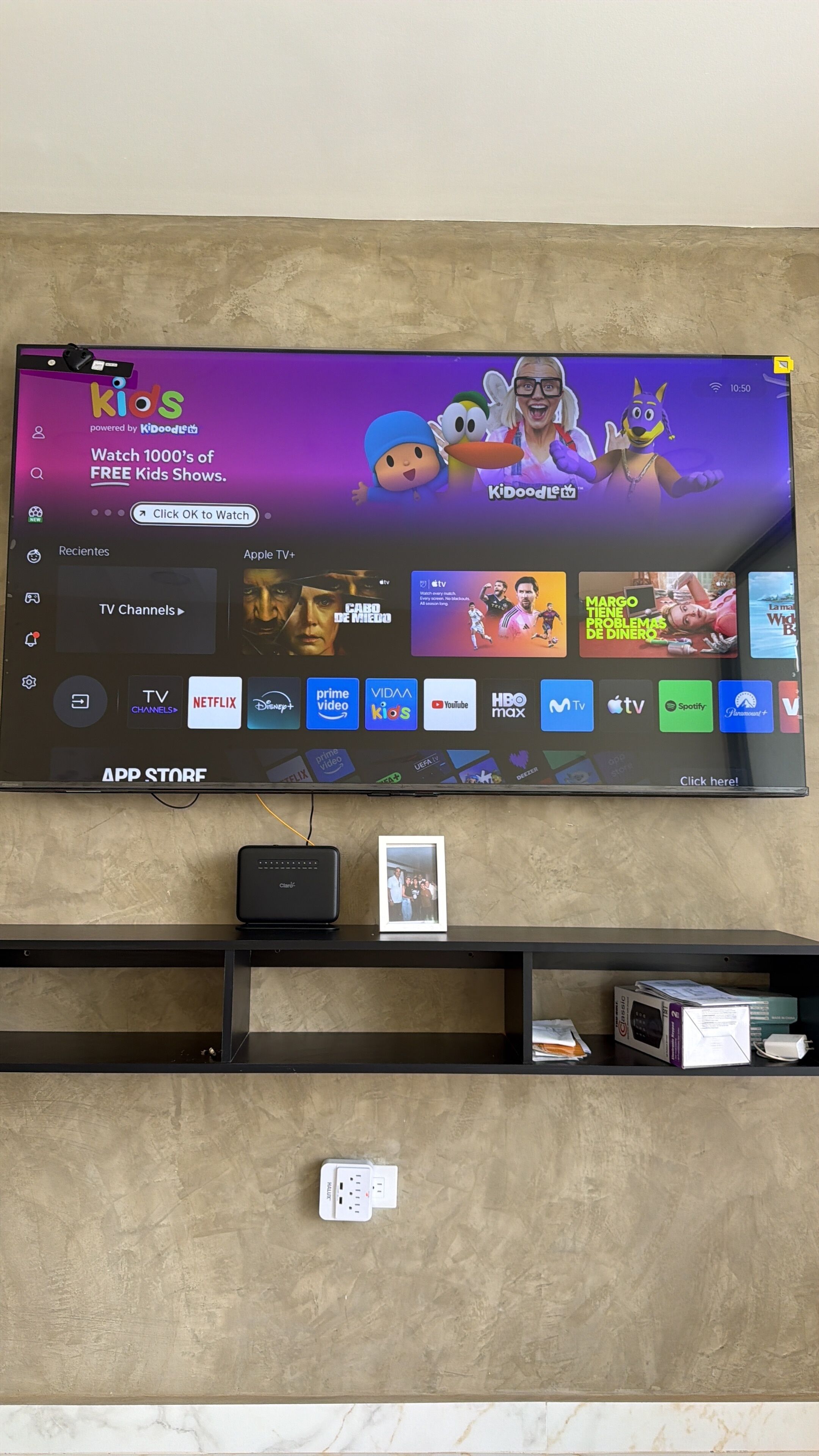 A flat-screen TV mounted on a wall displaying a streaming service interface with various app icons.
