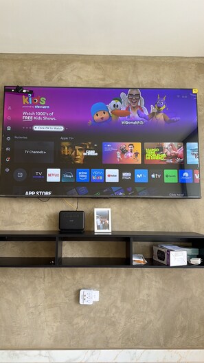 Televisor de pantalla plana montado en la pared mostrando una interfaz de servicio de transmisión con varios iconos de aplicaciones.