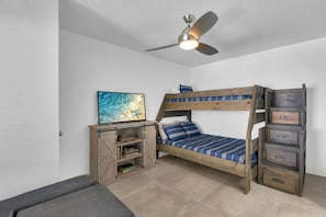 Ein Stockbett mit Schreibtisch und Regalelement, ein Deckenventilator und ein Bild an der Wand.