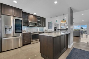 A modern kitchen with stainless steel appliances, dark cabinetry, and a large island. - Top-Floor Coastal Escape | Bay Views | Naples Retreat (Naples)