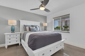 A bedroom with a bed, nightstands, a ceiling fan, and a window with blinds. - Top-Floor Coastal Escape | Bay Views | Naples Retreat (Naples)