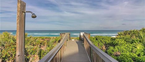A wooden boardwalk leading to a beach with ocean views.