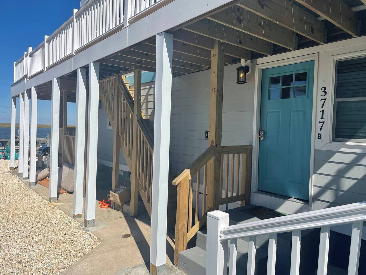 A coastal building with a wooden deck, a blue door, and a number '3717' on the wall.
