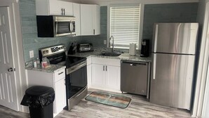 A modern kitchen with stainless steel appliances, white cabinetry, and a tiled backsplash.