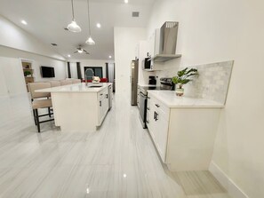 Uma cozinha moderna com ilha central, armários brancos e backsplash revestido de azulejos.