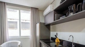 Uma cozinha moderna com fogão embutido, pia e janela com cortinas.