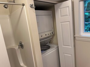 Et badeværelse med badekar, toilet og et vindue med udsigt til træer.