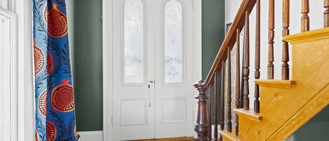 A staircase with wooden balusters, a white door with glass panels, and a blue curtain with a pomegranate pattern.