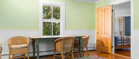 A room with a dining table and chairs, a window, and a door leading to another room.