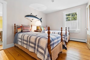 A bedroom with two beds, a ceiling fan, a window with a view, and a wall-mounted shark decoration. - Pom Cottage - 3BR Waterfront Cottage Near Acadia (Prospect Harbor)