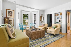 Ein Wohnzimmer mit einer Couch, Sesseln, einem Couchtisch und einem Bücherregal.