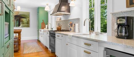 Une cuisine moderne avec des meubles blancs, une cuisinière et une machine à café.