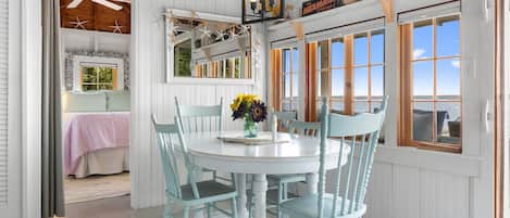 Una habitación con una mesa redonda, cuatro sillas, un florero con flores y un letrero que dice 'The Mermaid Lounge'.