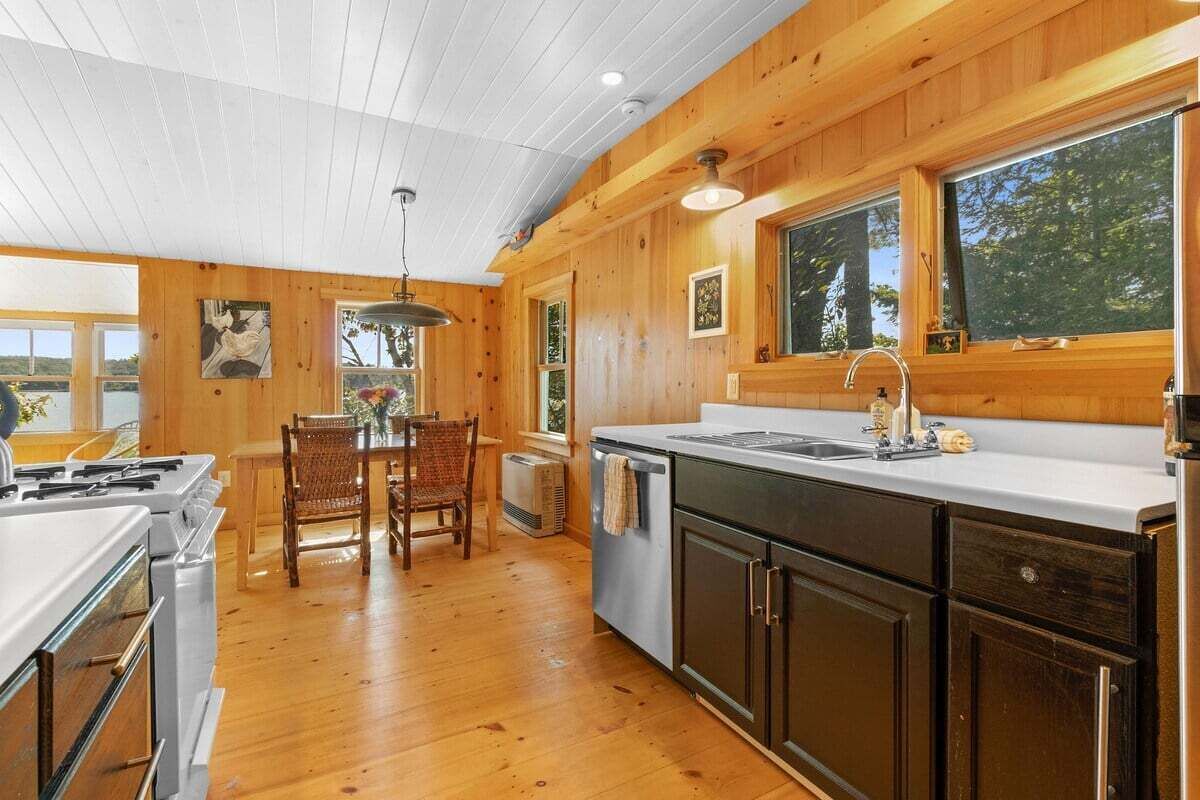 A kitchen with wooden walls, a dining area with a table and chairs, and a large window.