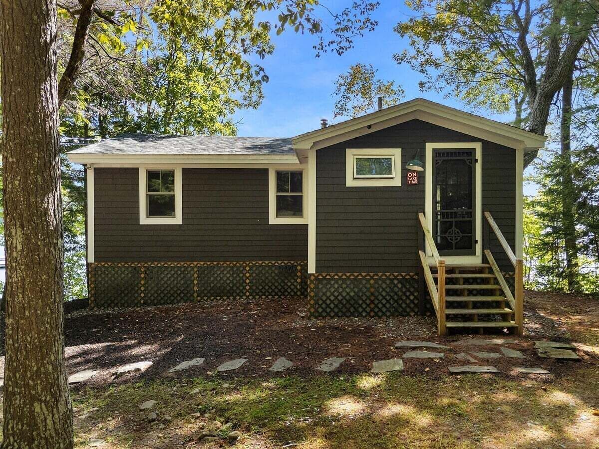 Une cabane à deux étages, dotée d’une porte d’entrée, d’un petit porche et d’un escalier menant à l’étage supérieur.