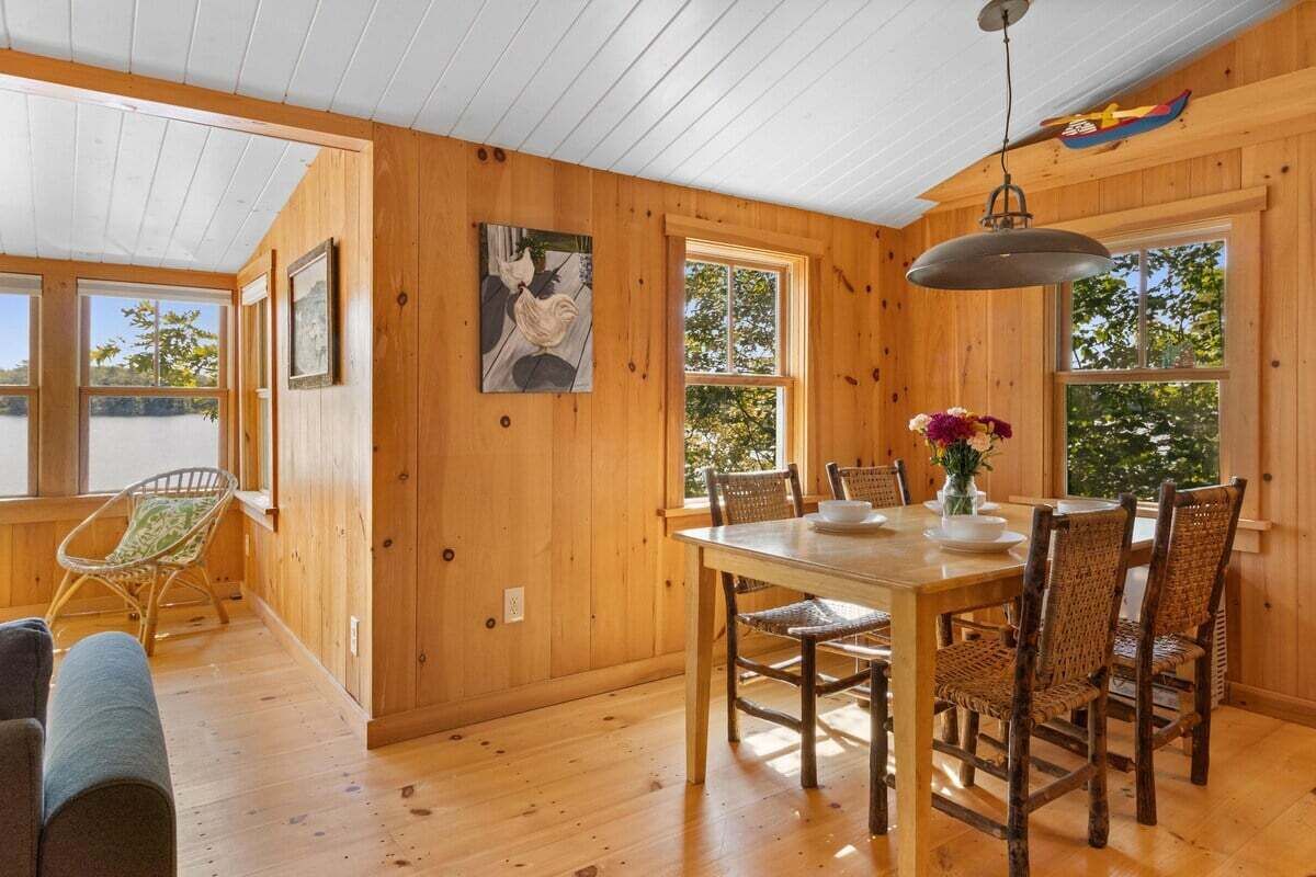 Un interior de madera con una mesa de comedor, sillas y una lámpara colgante.