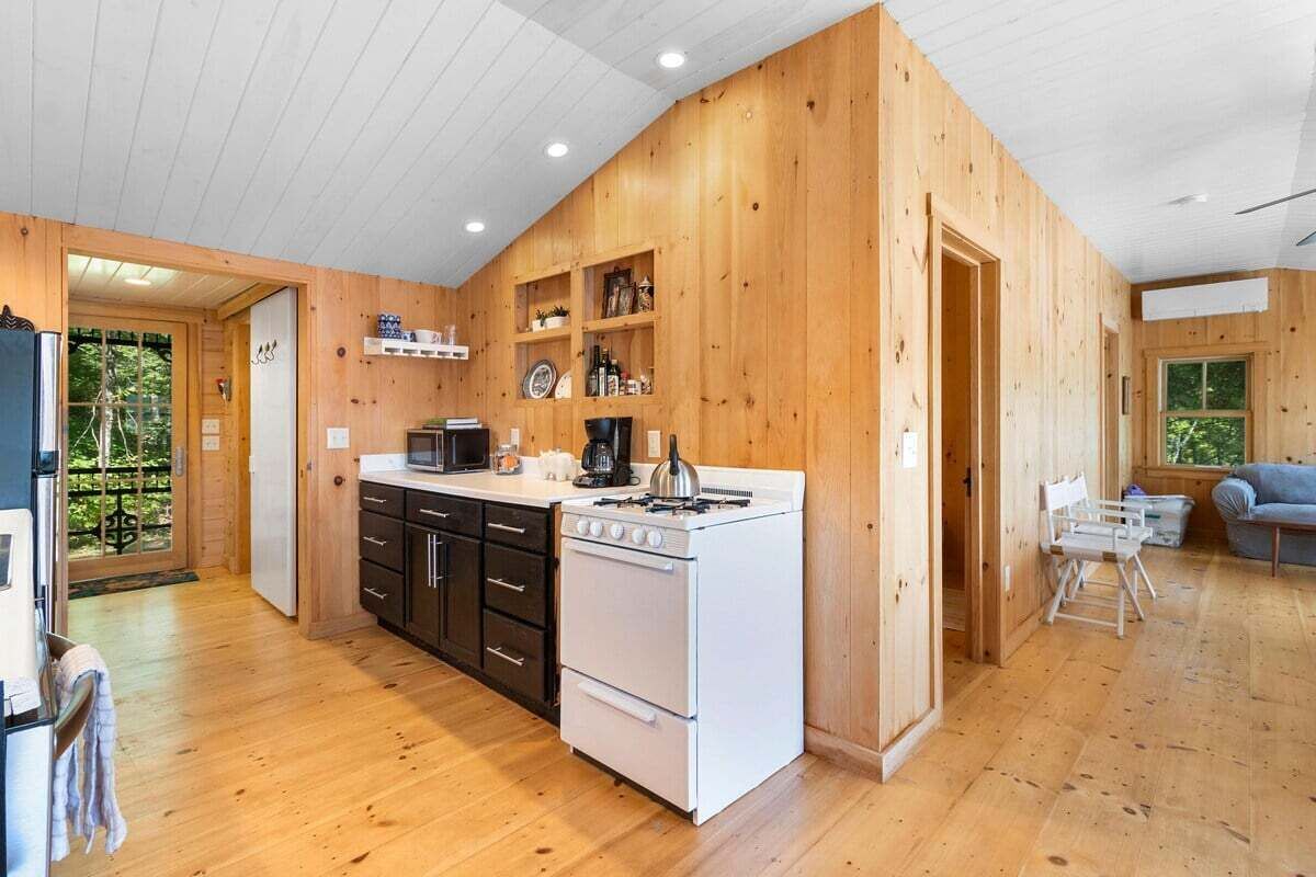 Eine moderne Küche mit Holzwänden, weißen Geräten und Blick auf Grünflächen.