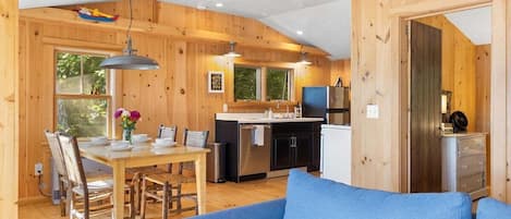 Een houten cabin met een eethoek, keuken en een blauwe bank.
