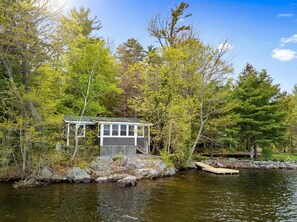 Eine Hütte am See, umgeben von Bäumen.