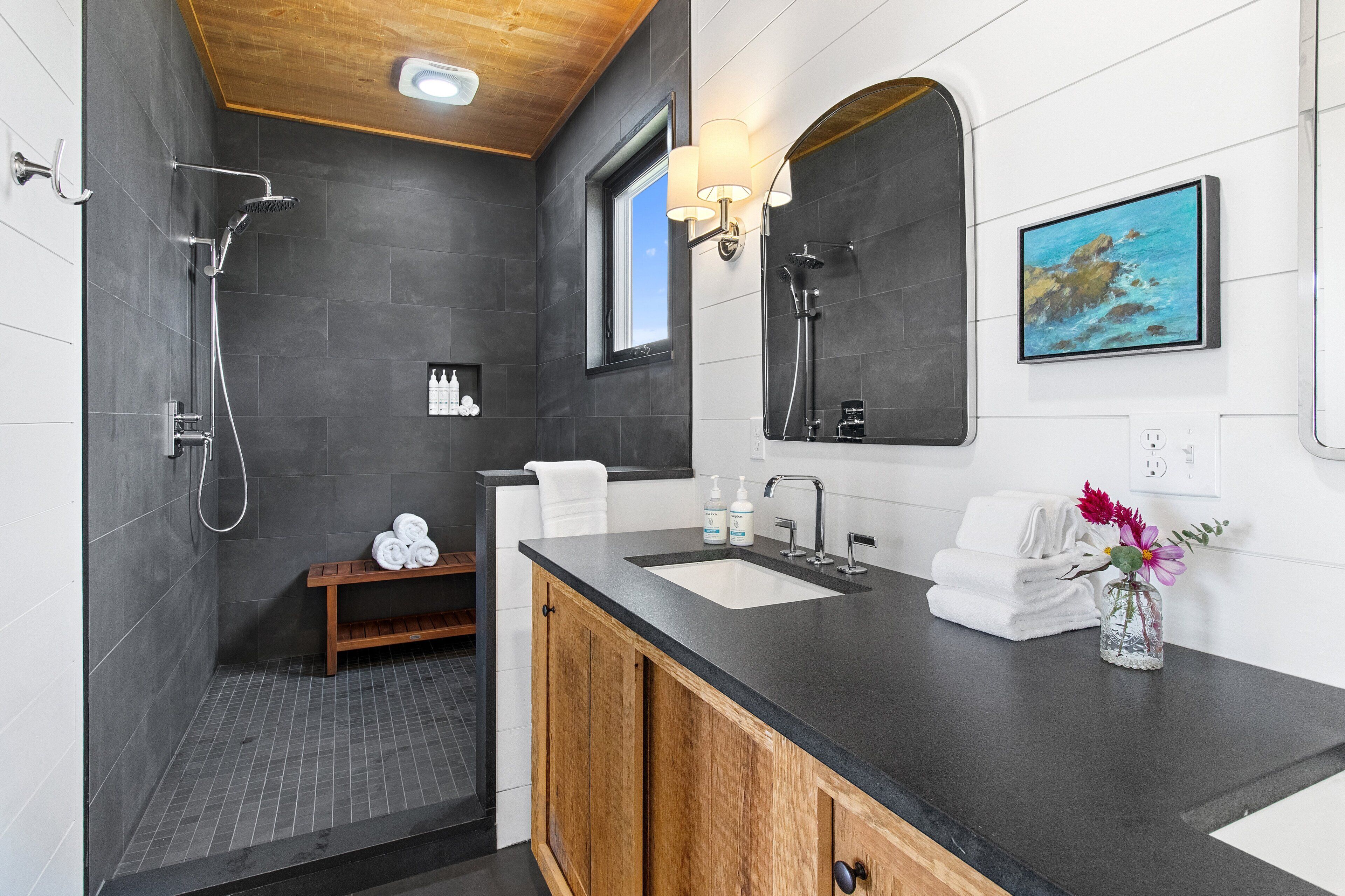 A modern bathroom with a shower, a vanity with a sink, and a large mirror.