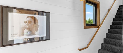 Un escalier avec des rampes en bois et un cadre photo fixé au mur.