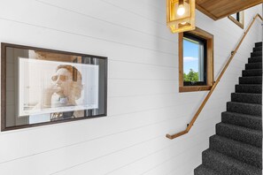 A staircase with wooden handrails and a wall-mounted picture frame. - Sweet Caroline at Salt Farm - Waterfront King Suite With Ocean Access, Balcony, Wifi, and AC (Sullivan)