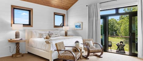 Une chambre avec un grand lit, deux fauteuils, une table et une vue sur l’extérieur.