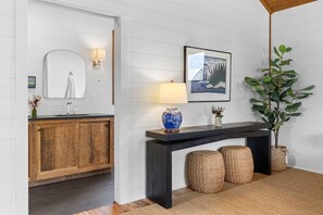 Un baño moderno con tocador de madera, un espejo, un lavamanos y un aplique de pared.