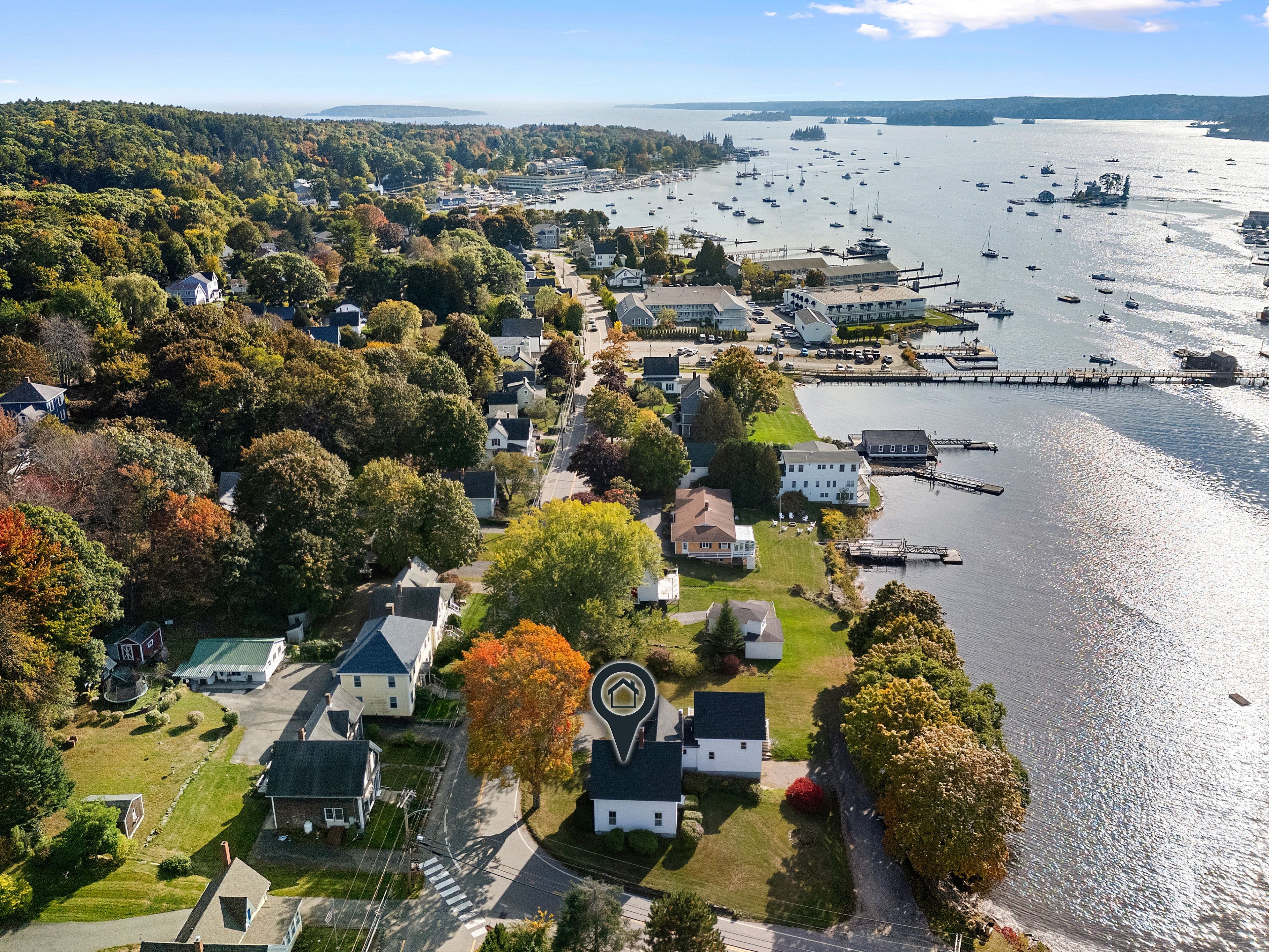 An aerial view of a coastal town with houses, a marina, and boats.