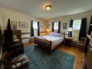 Ein Schlafzimmer mit einem Einzelbett, Nachttischen, einem Schreibtisch, einem Stuhl und einer Heizung.