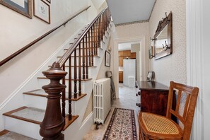 A staircase with wooden balusters, a radiator, a patterned rug, and a wooden chair. - One Atlantic 5BR Harbor View Maine Home, Close to Town, Deck (Boothbay Harbor)