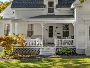 Ein weißes Haus mit Veranda, Eingangstür und kleinem Garten.