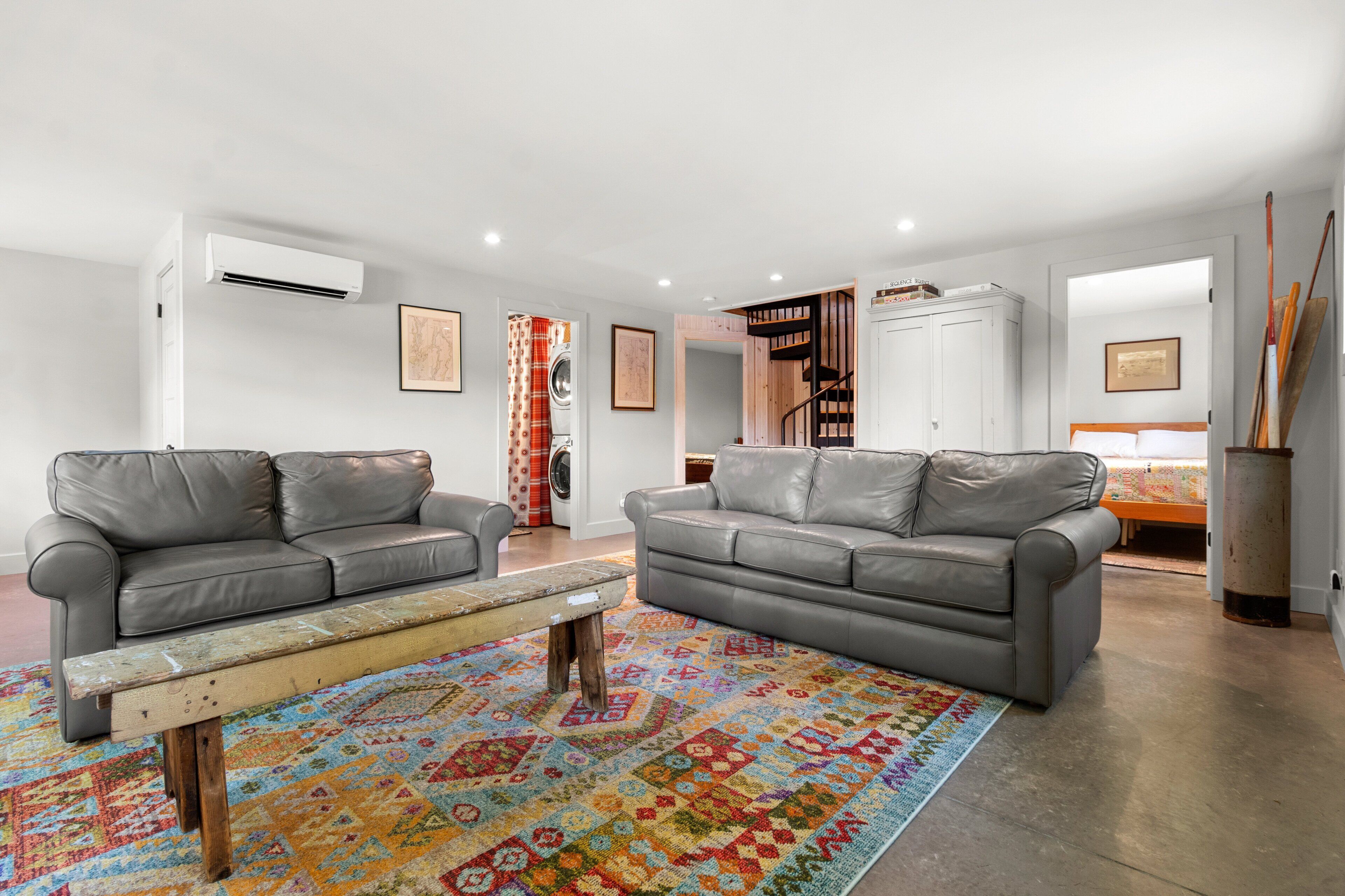 A living room with two grey sofas, a colorful rug, and a wooden coffee table.