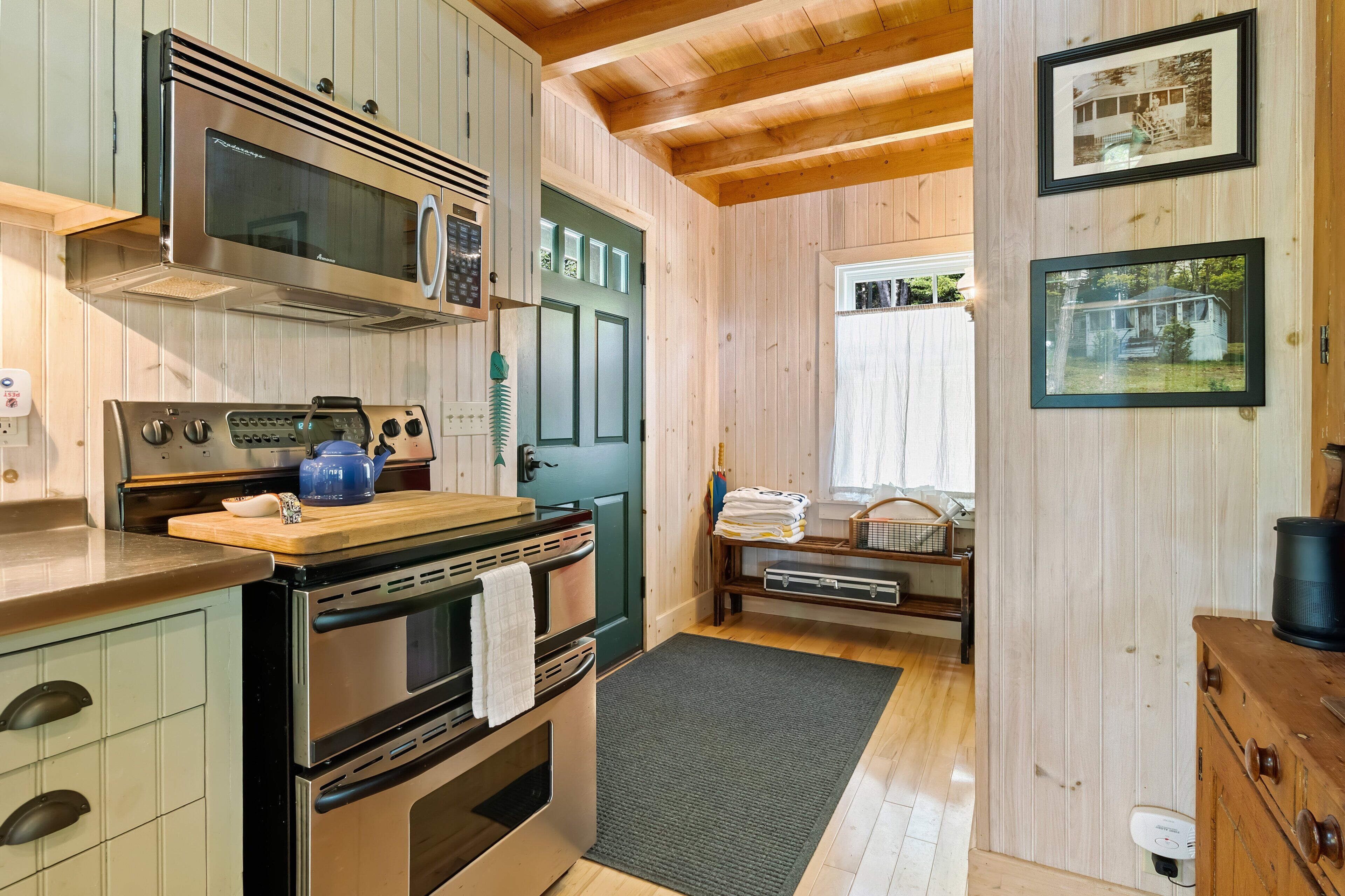 A kitchen with a microwave, oven, and a wooden countertop.