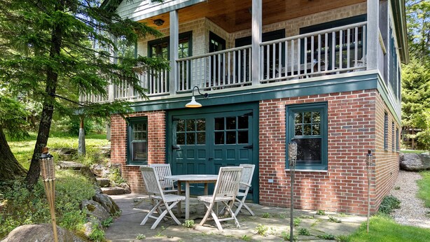 Ein zweistöckiges Haus mit Balkon, Eingangstür und einer Terrasse, komplett mit Tisch und Stühlen.