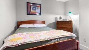 Ein Schlafzimmer mit einem Bett, einem Schminktisch, einem Nachttisch, einer Lampe und einem gerahmten Bild an der Wand.
