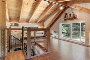 A wooden interior with a staircase, a window with a view, and a shelf with books. - The Boathouse (Bath)