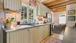 A kitchen with wooden cabinets, a large window, and an American flag. - The Boathouse (Bath)