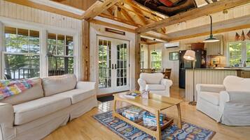 A spacious living room with a wooden ceiling, a sofa, a coffee table, and a view of the outdoors.