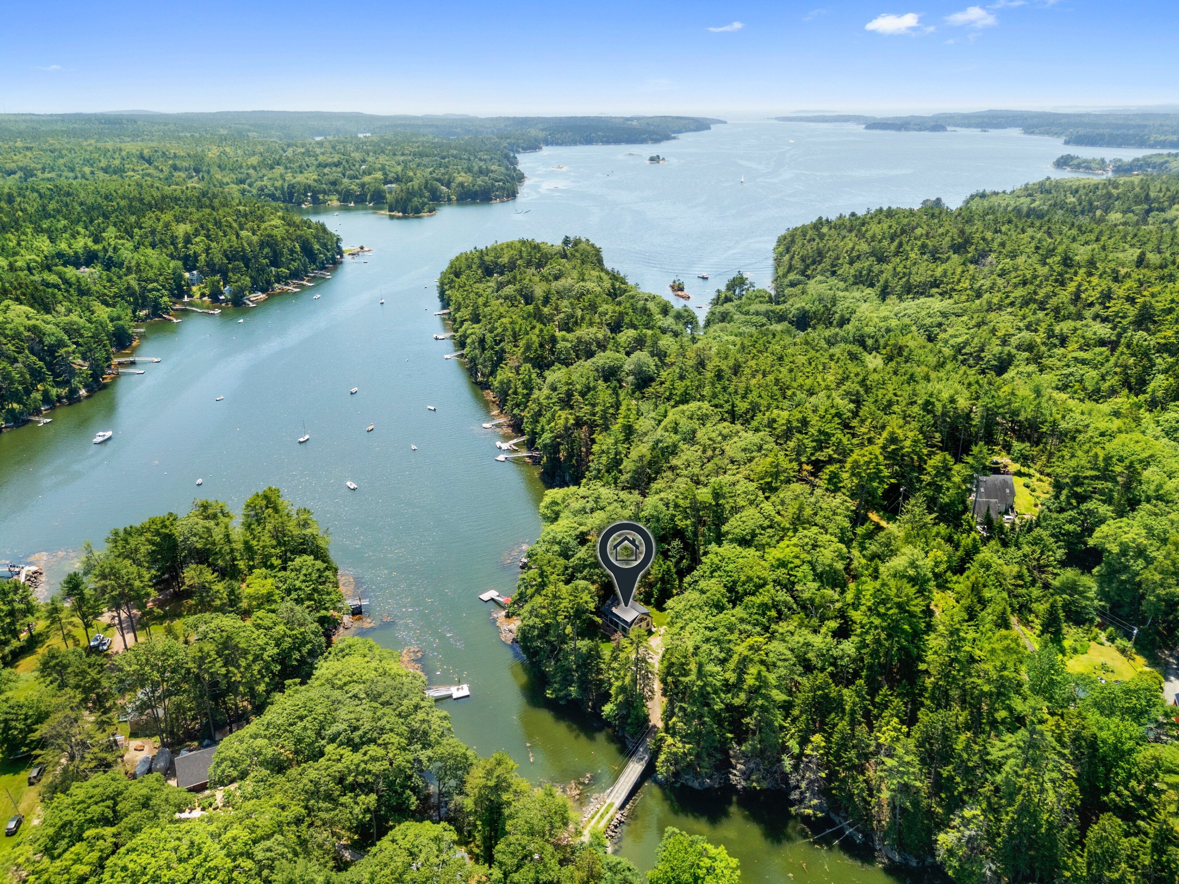 A river surrounded by dense forest, a small dock, and a house with a view of the water.