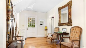A room with wooden flooring, a large ornate mirror, and two upholstered chairs. - La Maisonette - Historic Renovated 6 BR Downtown Bar Harbor (Bar Harbor)