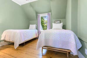 A room with two single beds, a window with purple curtains, and a wooden floor. - La Maisonette - Historic Renovated 6 BR Downtown Bar Harbor (Bar Harbor)