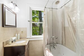 Et badeværelse med badekar, et vindue, en vask og et spejl.