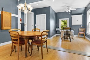 Un espace repas comprenant une table et des chaises en bois, un lustre et un ventilateur de plafond.