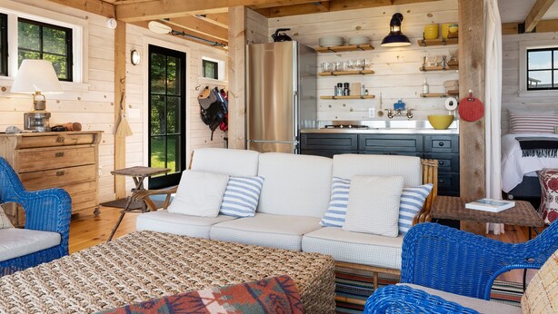 A cozy cabin interior with a sofa, wicker chairs, a dining area, and a kitchen. - Aril Cottage-waterfront Escape With Ocean Views (Prospect Harbor)