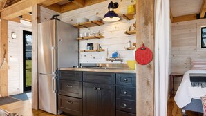 A compact kitchen with a refrigerator, wooden cabinets, and a sink. - Aril Cottage-waterfront Escape With Ocean Views (Prospect Harbor)