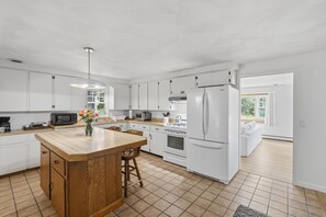 A modern kitchen with white cabinets, a wooden island, and a stainless steel refrigerator. - 4-bedroom house in lovely Narragansett with cool ocean breeze (Narragansett)