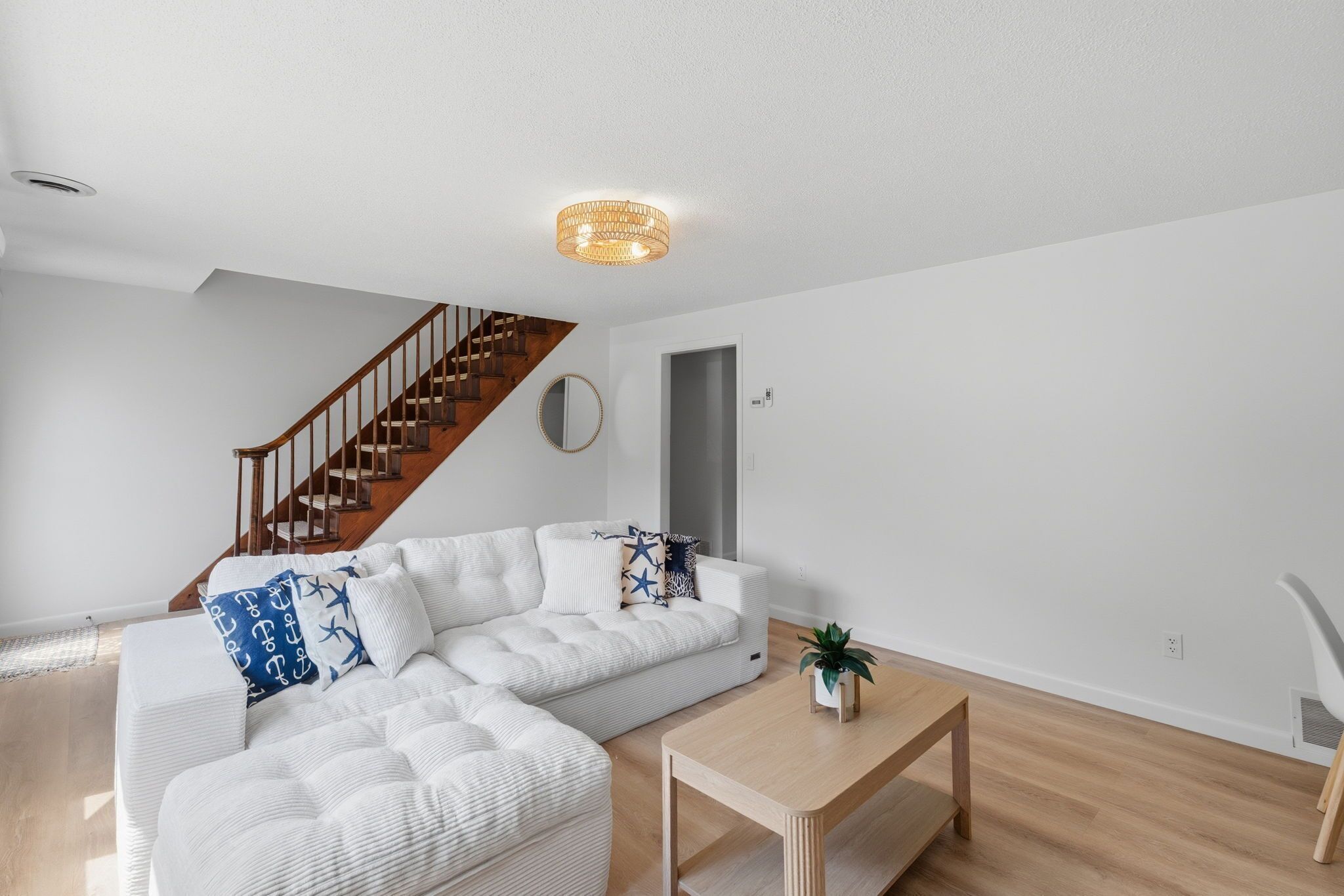 A modern living room with a sectional sofa, a wooden staircase, and a small table.