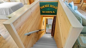 A wooden staircase with a sign reading 'SHORE ROAD MARINA.' - Riverbend Perch - River-view Retreat for 2 With Kitchen, Patio, AC, Wi-fi (Cushing)