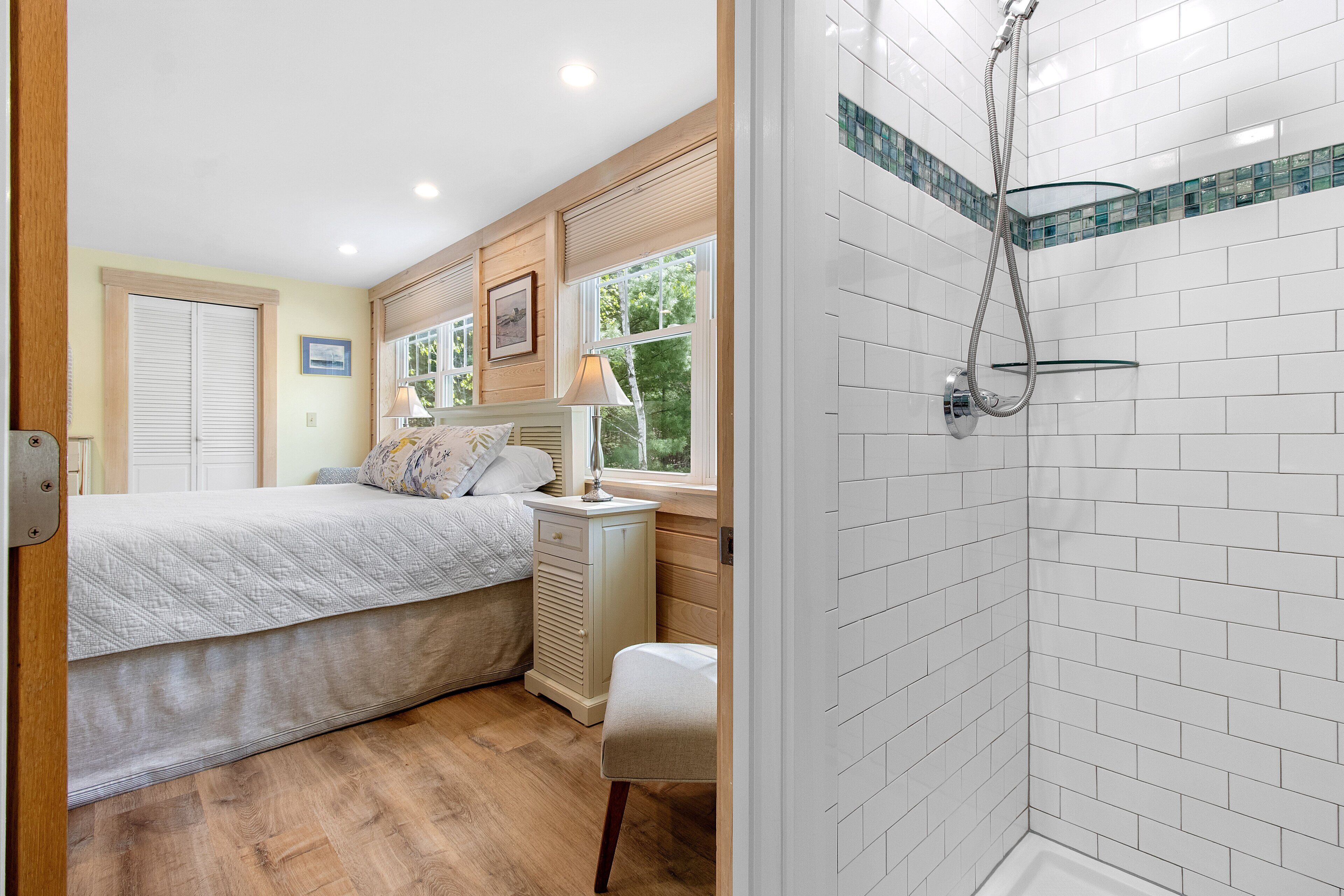 A bedroom with a bed, bedside table, lamp, and window.